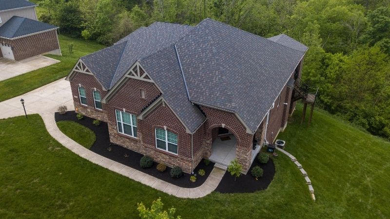 A residential brick home with a new shingle roof. The photo was taken with a drone so the full roof is visible.