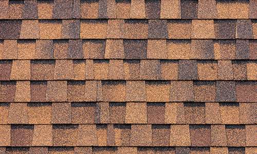 Overhead view of clean brown architectural asphalt shingles installed in a repeating pattern.