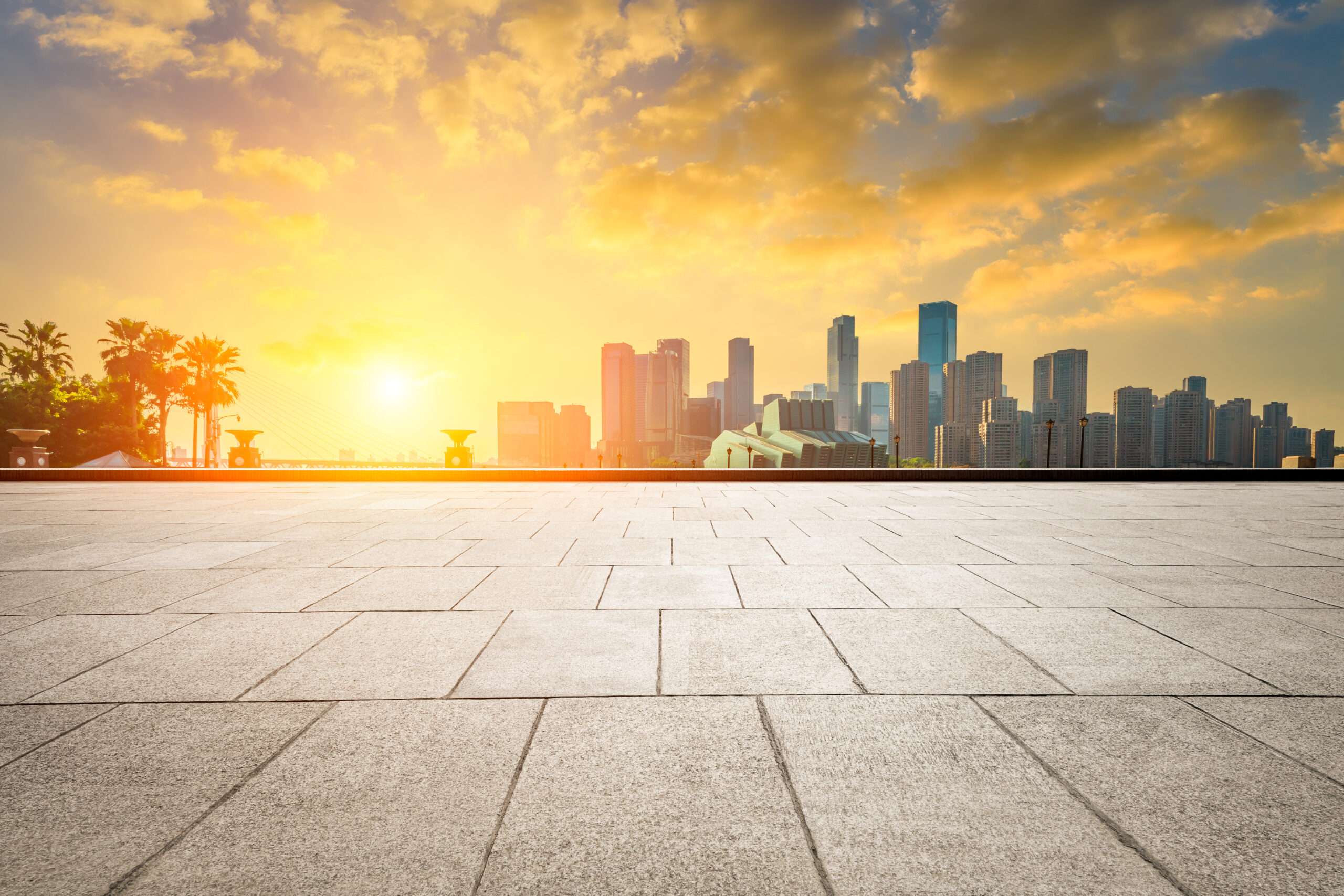 Wide view of a modern urban skyline seen from an empty rubber building rooftop plaza at sunset.