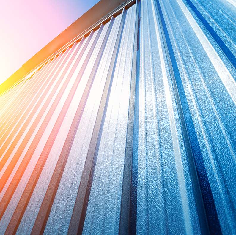 A colorful, abstract upward view of a commercial building exterior with vibrant metal siding or roofing panels.