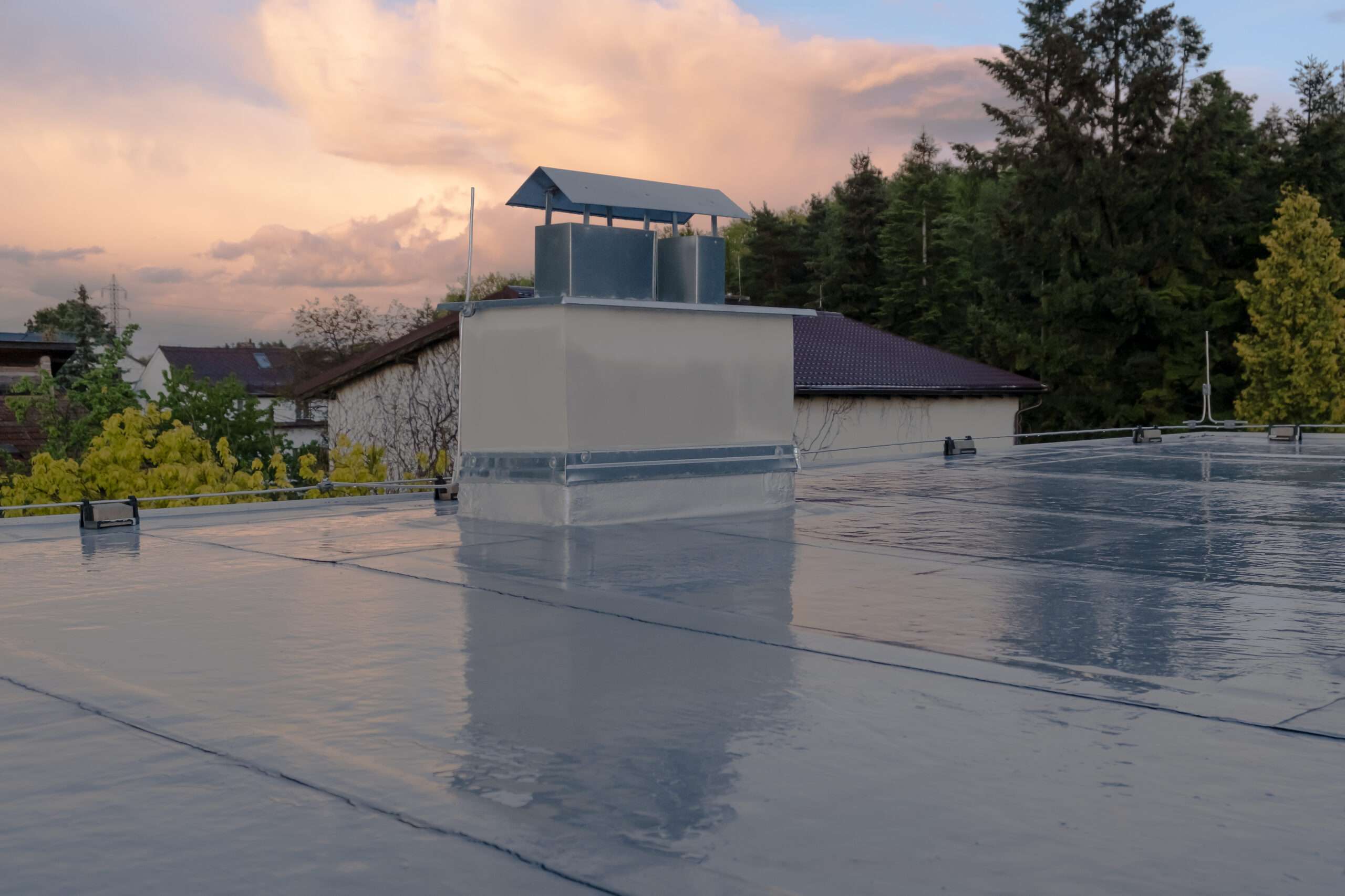 Wide view of a flat rubber commercial roof installation featuring a central concrete and metal HVAC utility housing structure.