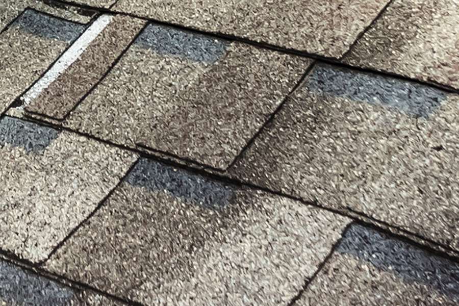 An educational module image highlighting a faulty roof installation with misaligned asphalt shingles and exposed seams, topped with an alert icon warning about unqualified workmanship.