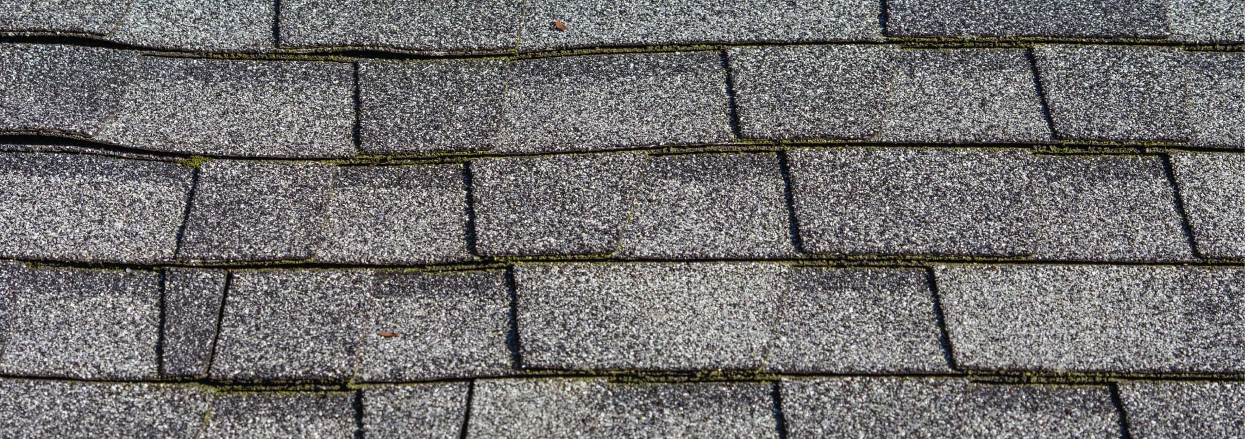 Close-up of a buckled and uneven asphalt shingle roof system caused by multiple overlapping layers from an improper roof-over installation in Cincinnati.