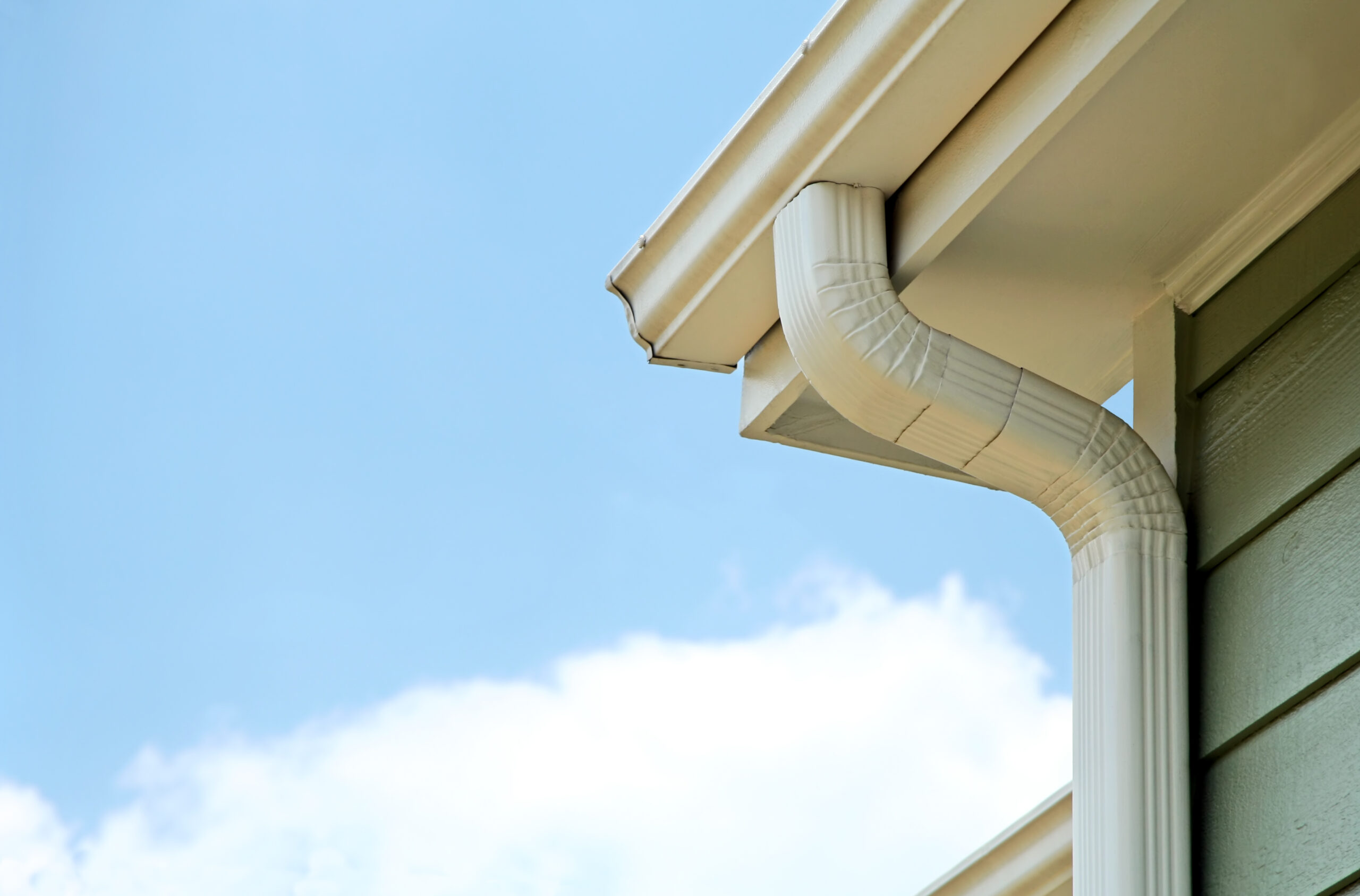 A gutter and downspout installed along the roof of a residential home.